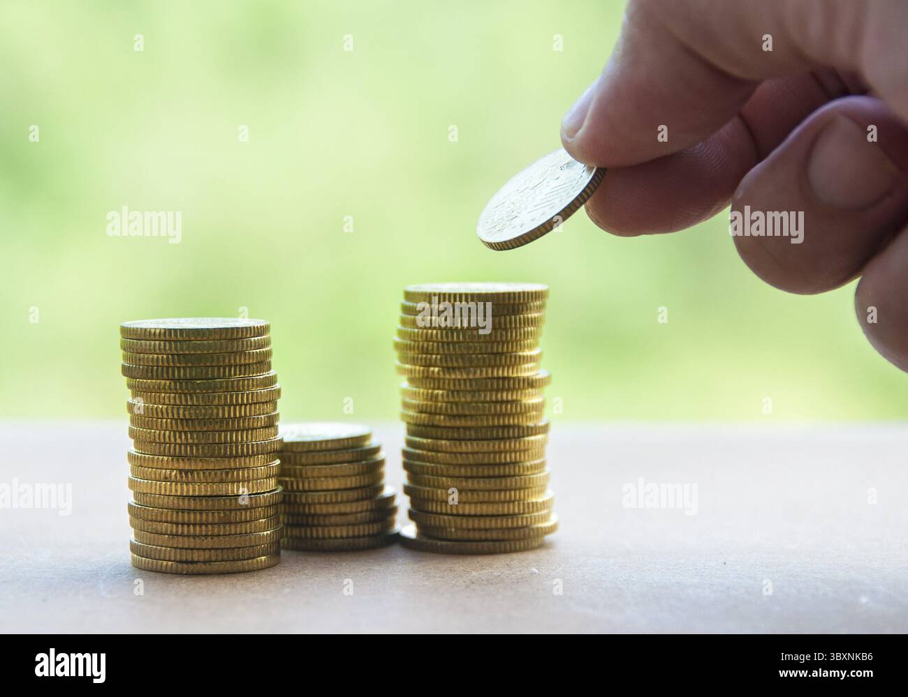 Main mettant la pièce d'or sur une pile de pièces. Concept de richesse et d'espace de copie Banque D'Images