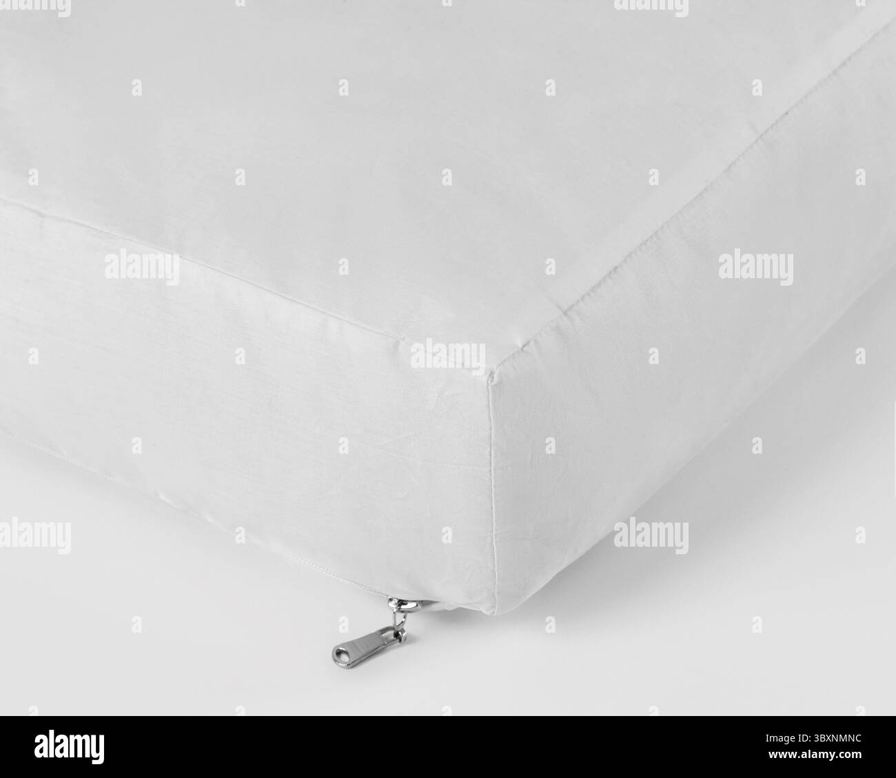 Gros plan d'un coussin carré blanc immaculé doté d'une fermeture éclair discrète, reposant sur un fond blanc propre Banque D'Images