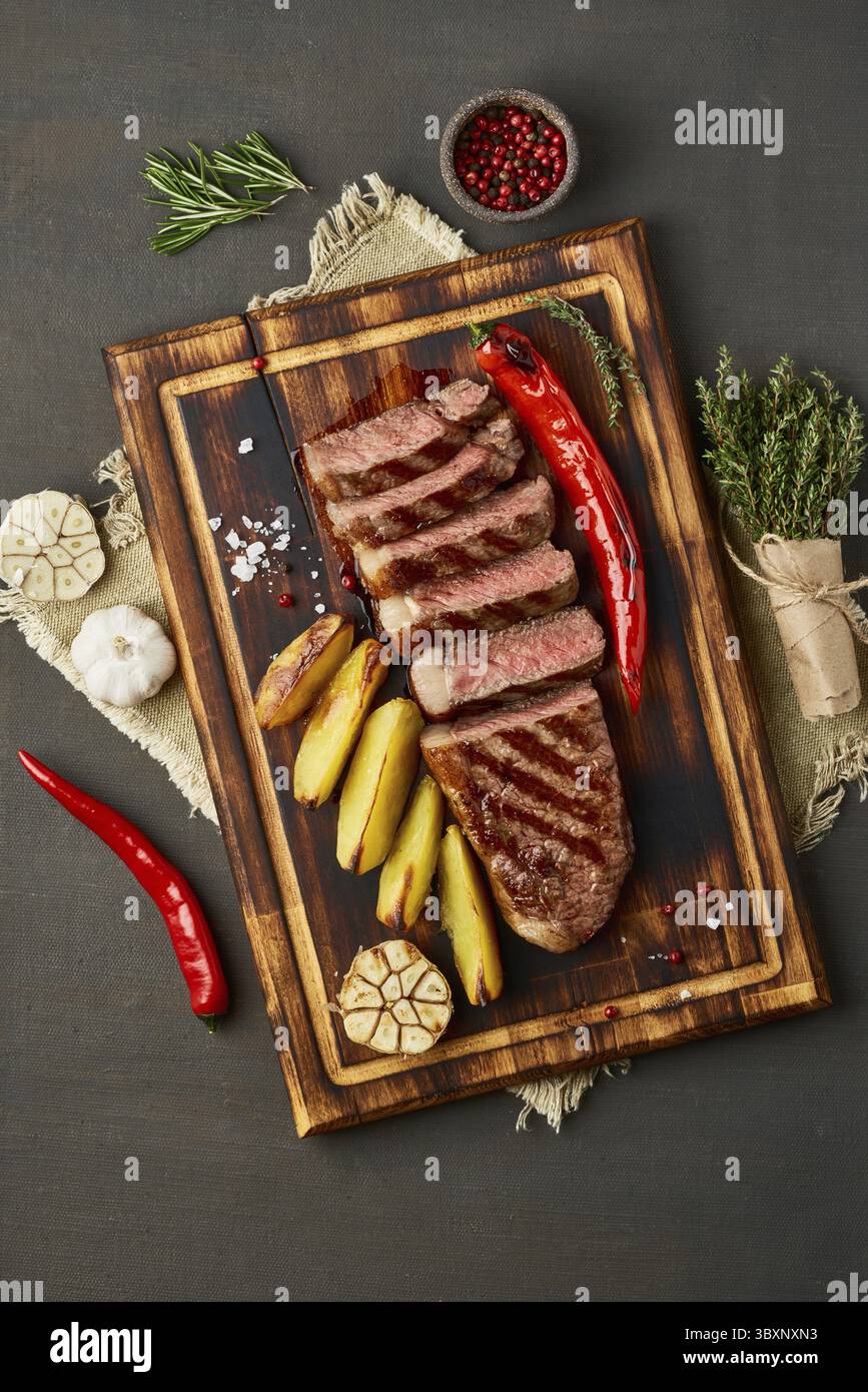 Régime keto cétogène steak grillé de bœuf frit, striploin, pommes de terre tranchées à bord de la table marron foncé. Recette de nourriture Paleo avec morceau haché de Banque D'Images