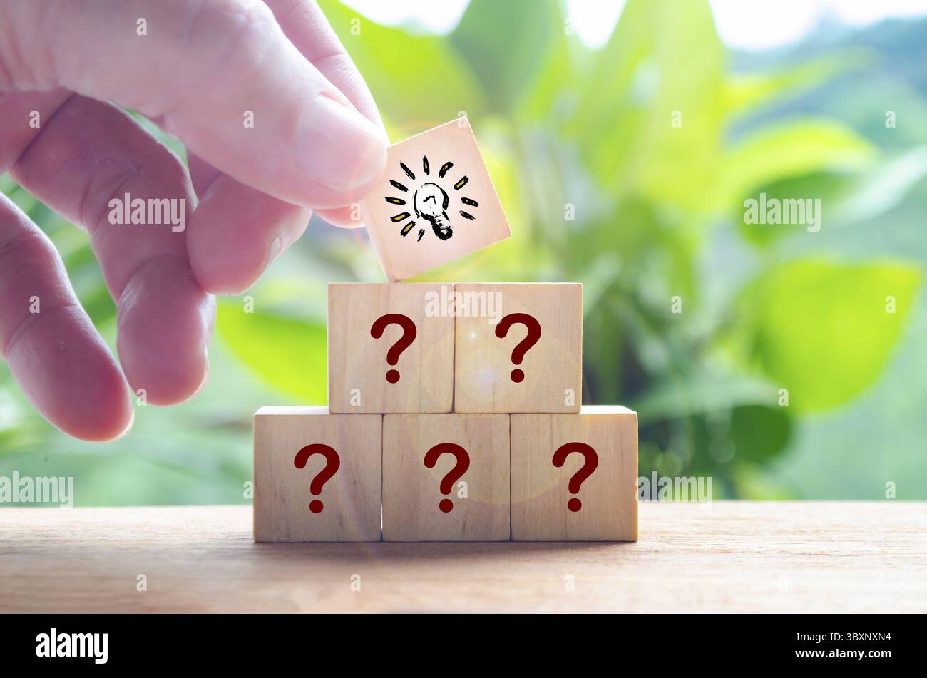 Main mettant cube en bois avec ampoule sur le dessus de l'autre symbole de point d'interrogation. Concept d'idée commerciale Banque D'Images