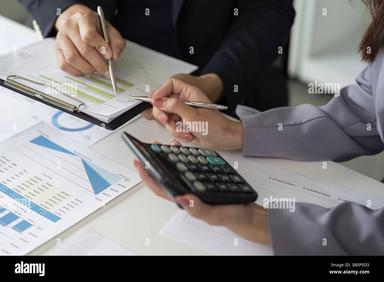 Une équipe est engagée dans la discussion des rapports financiers, assurant un examen détaillé des données afin d'améliorer leur stratégie de planification financière. Met en surbrillance l'imp Banque D'Images