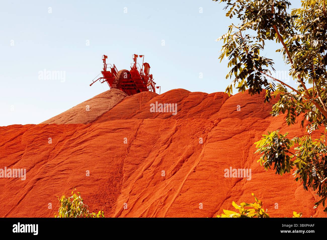 convoyeur derrière le monticule versant de la bauxite sur la terre rouge du site d'extraction de pieux Banque D'Images