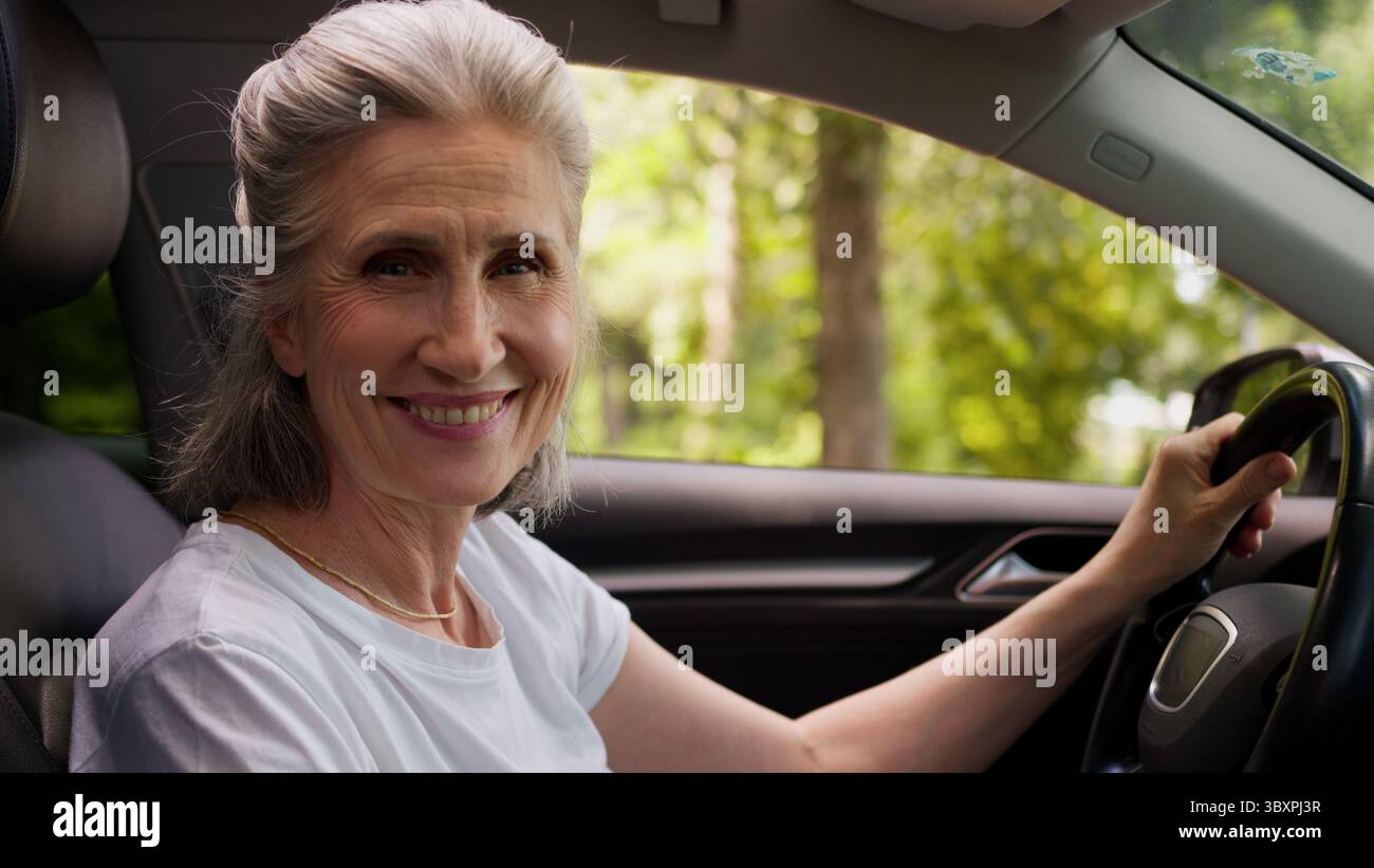 Heureux souriant caucasien mature senior femme propriétaire d'automobile femme grand-mère conducteur d'automobile assis à l'intérieur de la nouvelle voiture électrique moderne Banque D'Images