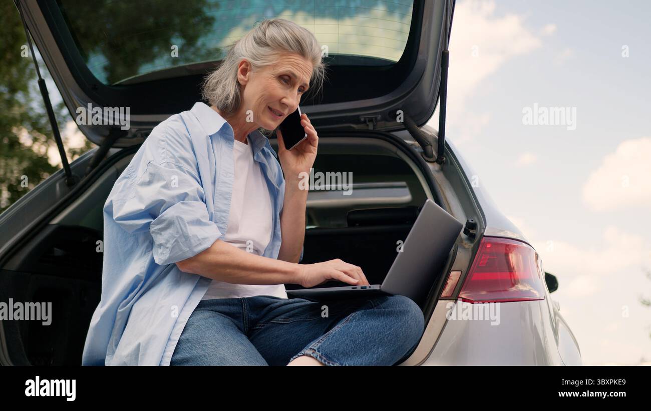 Caucasian senior mature femme d'affaires femme aux cheveux gris femme d'affaires voiture conducteur auto travailleur indépendant parlant appel de téléphone portable parler client Banque D'Images