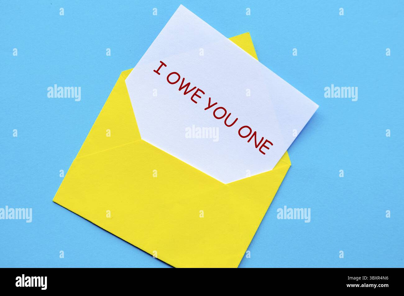 Enveloppe jaune sur une couverture bleue avec une carte blanche partiellement retirée avec je vous dois un texte Banque D'Images