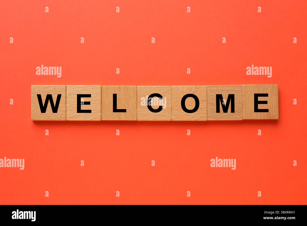 Mot Bienvenue fait de cubes en bois sur fond rouge, vue de dessus Banque D'Images