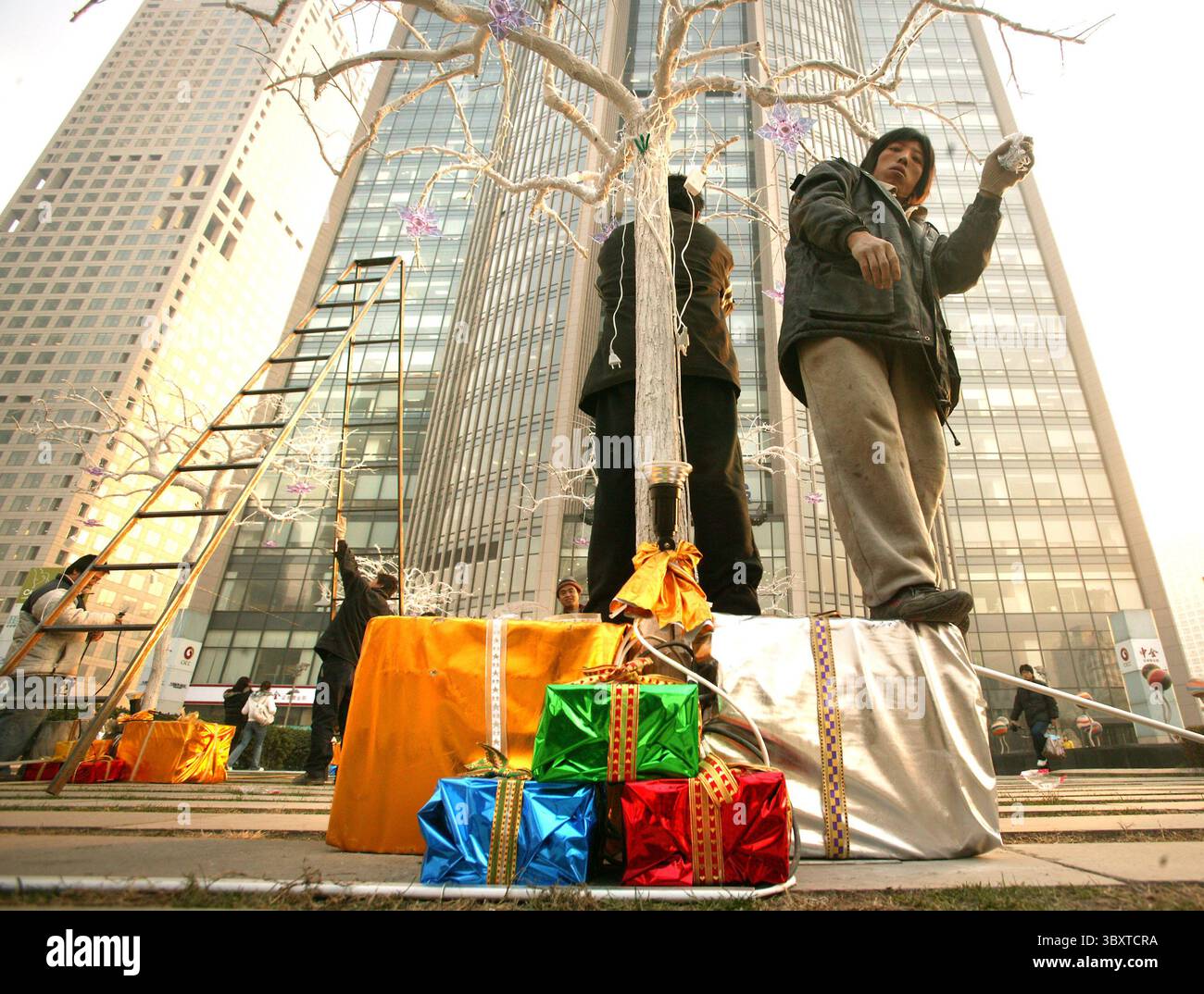28 novembre 2007, PÉKIN, CHINE : des travailleurs chinois ont installé des décorations de Noël devant des immeubles de bureaux dans le centre-ville de Pékin, Chine, le 28 novembre 2007. La capitale de la Chine est en proie à la fièvre de Noël, alors que de nombreux nouveaux centres commerciaux modernes de Pékin sont ornés de tresses, de chardons, de rubans et de cloches en prévision d'une demande croissante de marchandises et de magasins liés aux vacances. (Crédit image : © Stephen Shaver/ZUMA Press Wire) Banque D'Images