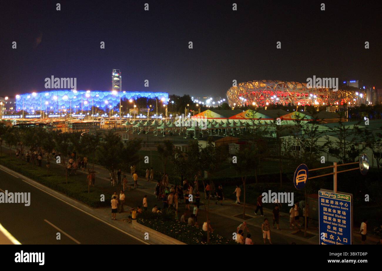 1er août 2008, PÉKIN, CHINE : les gens marchent autour du green olympique, avec le stade national olympique de Chine, également connu sous le nom de nid d'oiseau (R), et le Centre aquatique national olympique, également connu sous le nom de Watercube, la nuit juste une semaine avant la cérémonie d'ouverture des Jeux de 2008 à Pékin, le 1er août 2008. (Crédit image : © Stephen Shaver/ZUMA Press Wire) Banque D'Images
