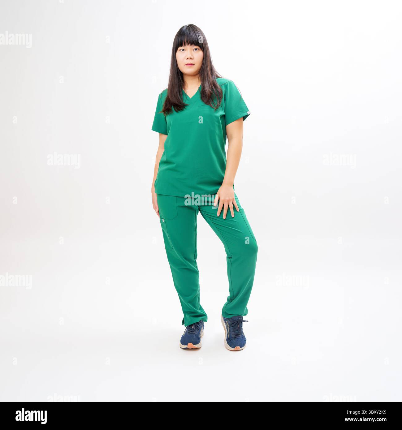 Travailleur de la santé en gommages verts debout sur fond blanc Banque D'Images