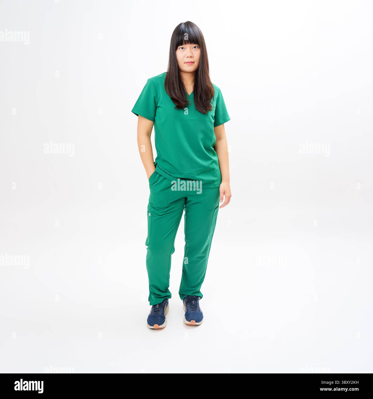 Travailleur de la santé en gommages verts debout sur fond blanc Banque D'Images