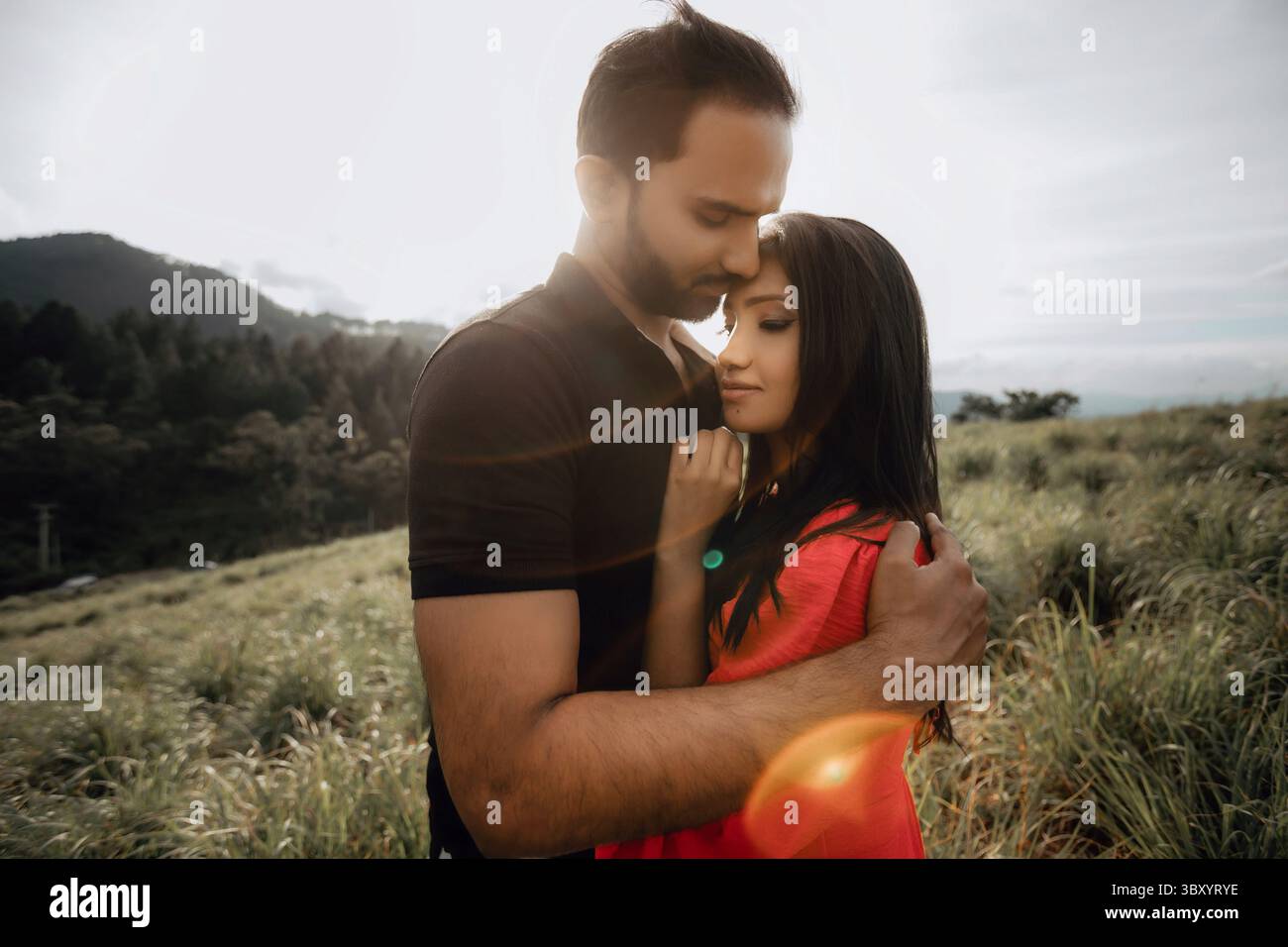Un beau couple embrassant dans un paysage extérieur pittoresque, symbolisant le confort et l'amour dans la nature. Banque D'Images