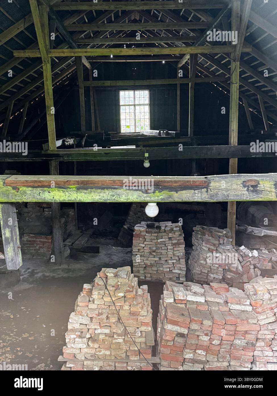 Fagervik : vue intérieure d'une ancienne grange avec poutres en bois et pieux de briques, atmosphère rustique, lumière douce à travers la fenêtre. Banque D'Images