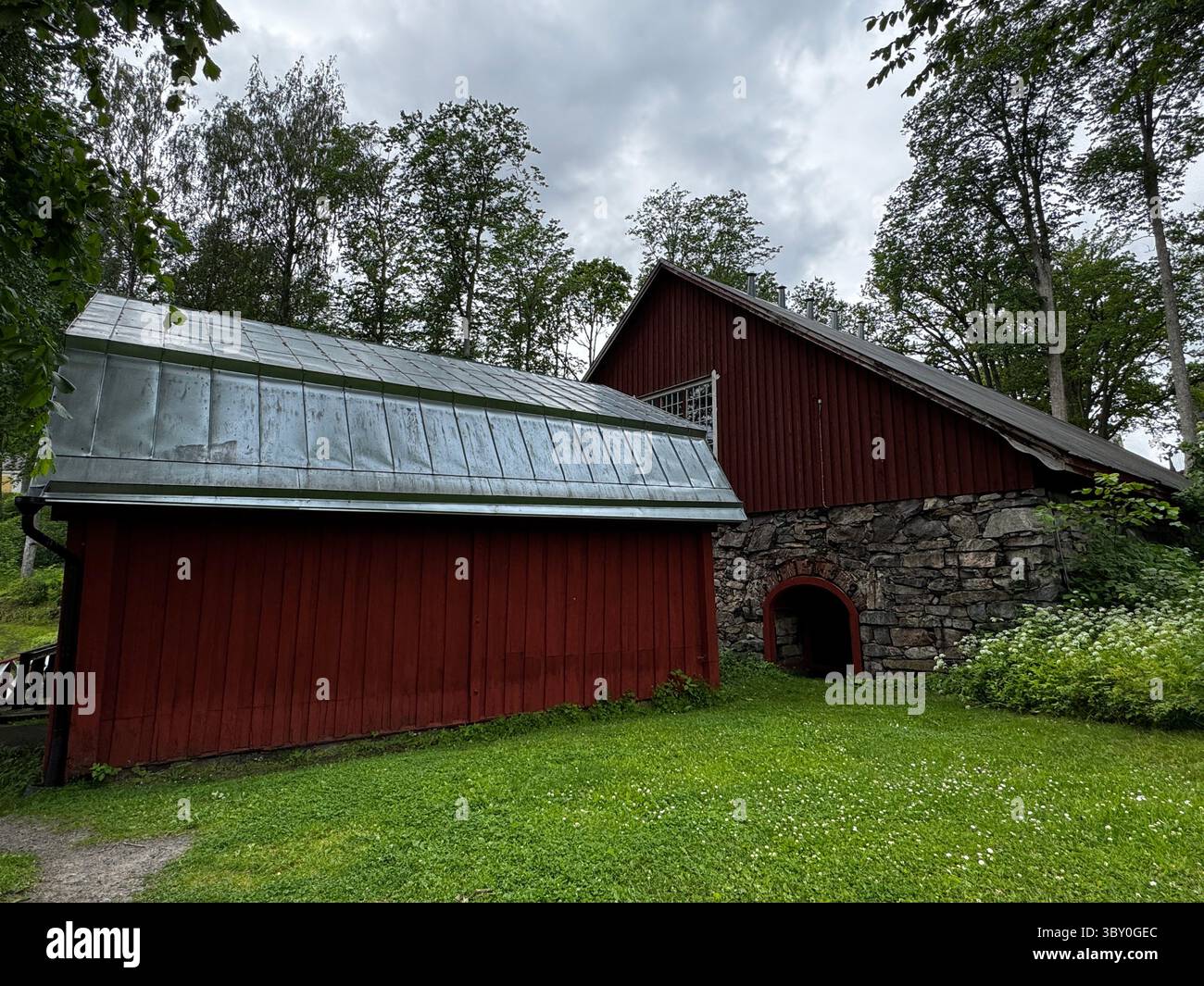 Fagervik, Finlande : deux granges rouges avec des fondations en pierre et des toits en métal dans la campagne finlandaise, ciel nuageux d'été au-dessus. - Image de stock capturée avec un smartphone