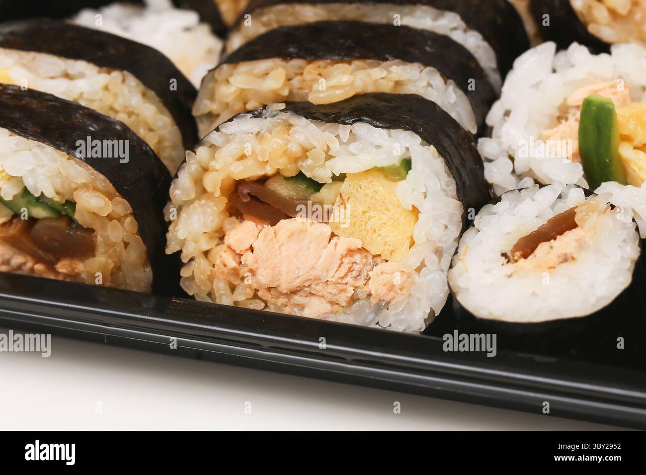 Petits pains de sushi japonais en gros plan. Maki frais avec riz et algues nori. Saumon, oeuf et légumes à l'intérieur. En-cas asiatique traditionnel. Banque D'Images
