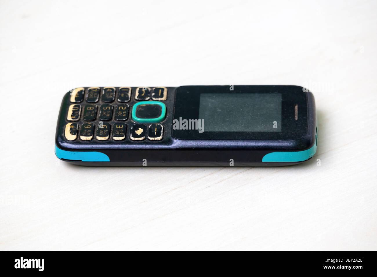 Téléphone vieilli avec boutons usés, boîtier décoloré et écran rayé, montrant des signes d'utilisation intensive. Parfait pour les thèmes de la technologie, nosta Banque D'Images