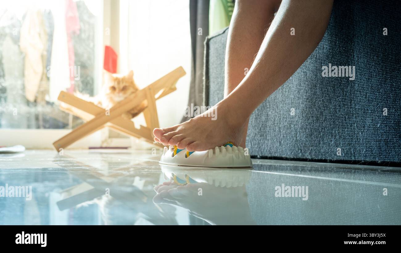 Femme utilisant un masseur de pied sur ses jambes, cherchant à soulager la douleur et l'inconfort des pieds à la maison. Banque D'Images