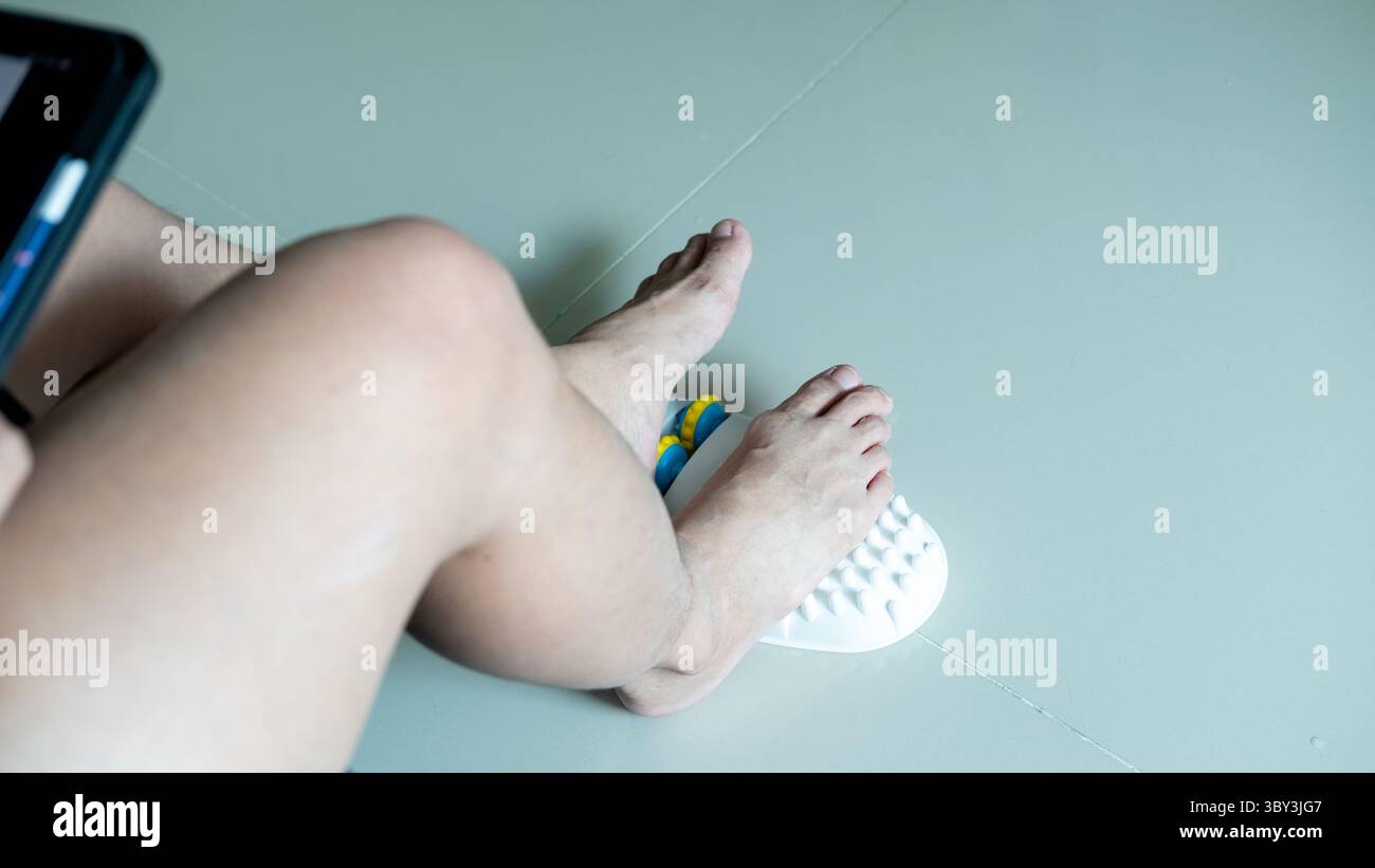 Masseur de pied utilisé sur les jambes d'une femme, fournissant un soulagement pendant qu'elle éprouve des douleurs aux pieds Banque D'Images