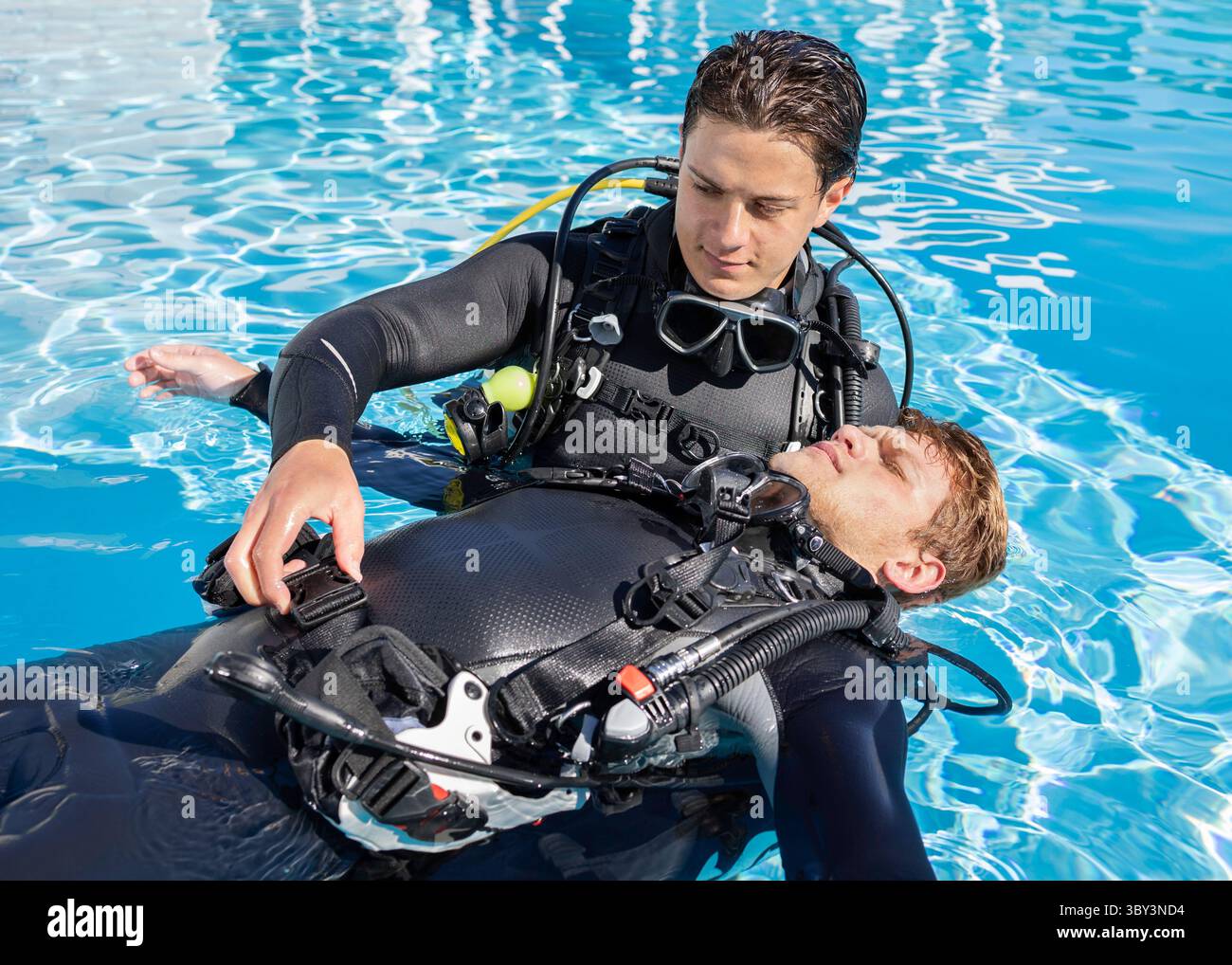 Deux plongeurs pratiquent le sauvetage de plongeurs dans une piscine, avec un plongeur flottant sur le dos et l'autre détachant son BCD Banque D'Images