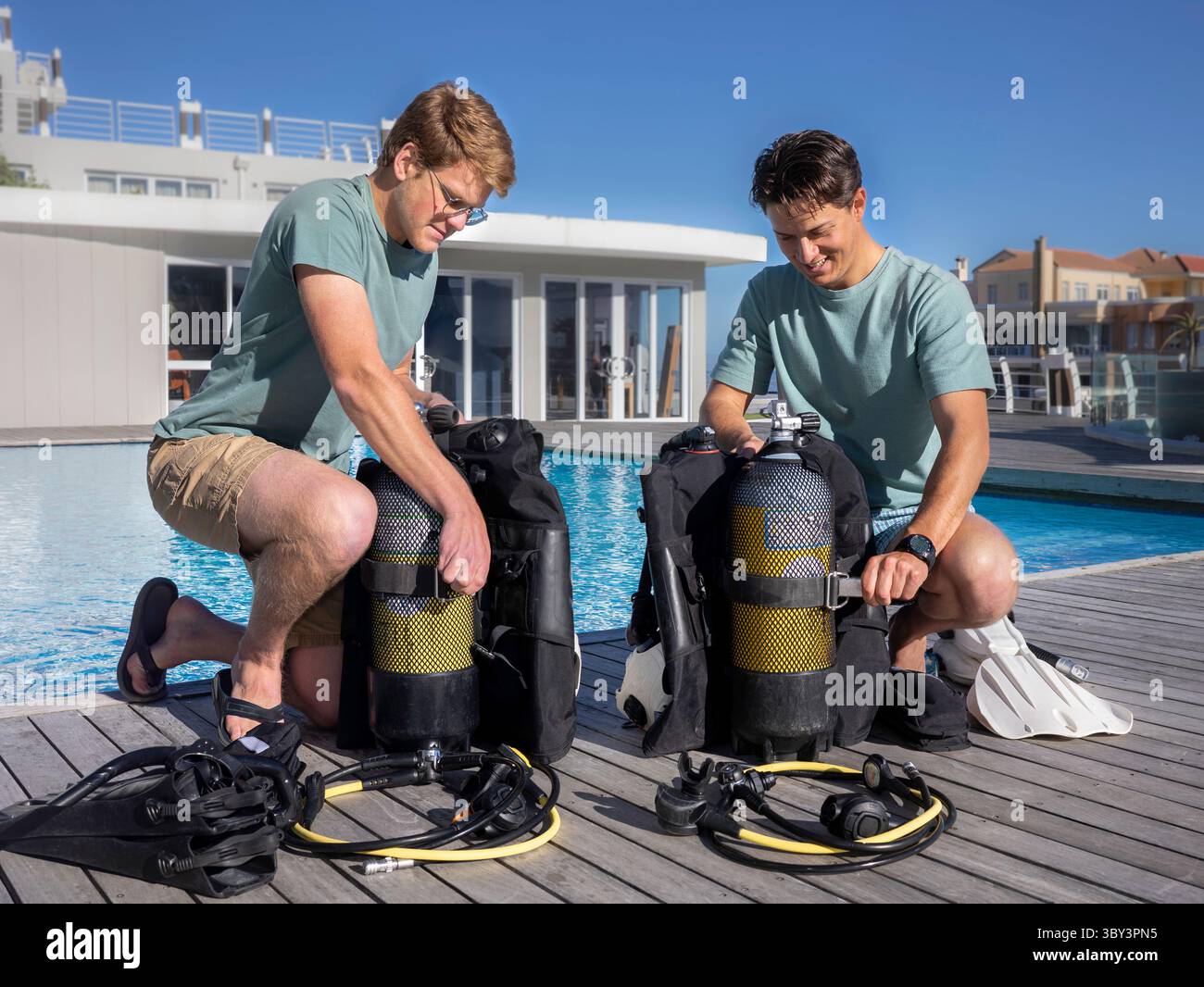 Deux plongeurs portant des vêtements d'été préparant leur équipement près d'une piscine dans un centre de plongée Banque D'Images