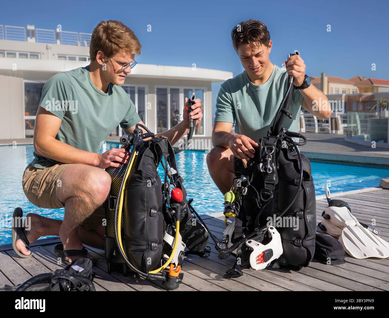 Deux plongeurs portant des vêtements d'été préparent leur équipement près d'une piscine dans un centre de plongée. Vérification du rapport en gonflant les BCD. Banque D'Images