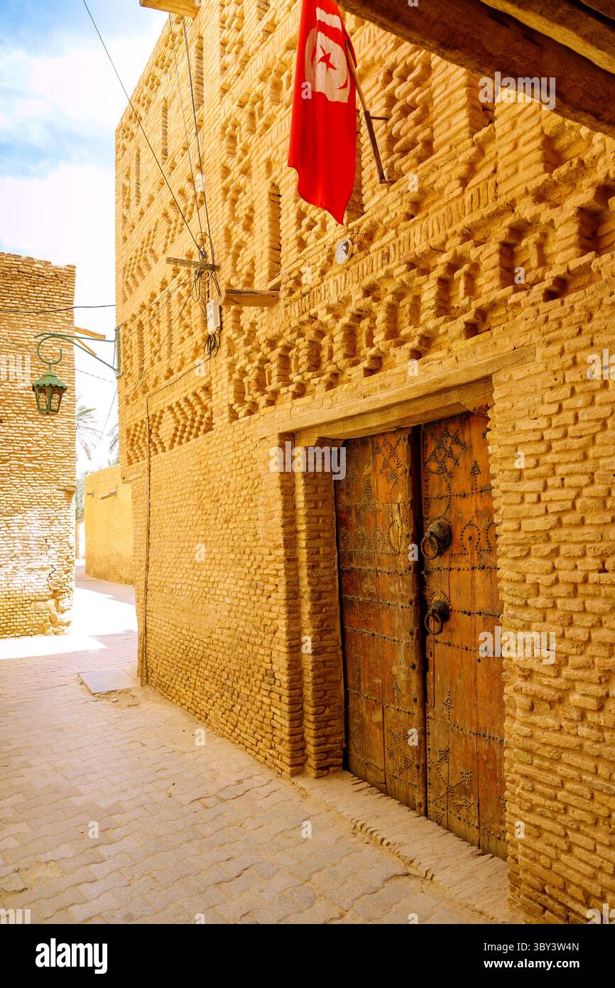 Architecture typique en briques de boue avec vieille porte en bois dans la vieille ville (Ouled el-Hadef, Médina) de la ville oasis de Tozeur, Tunisie Banque D'Images
