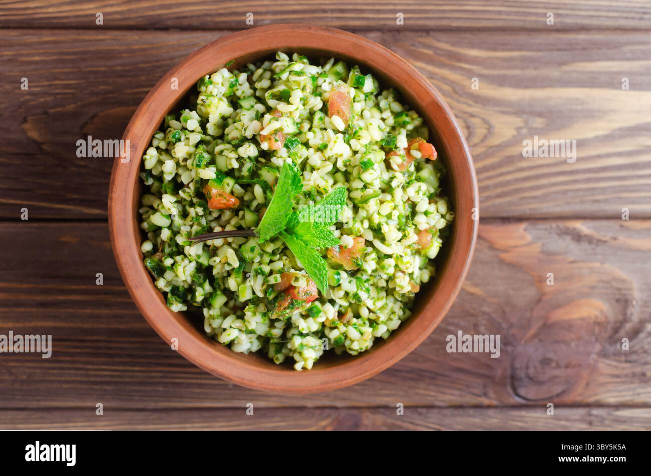 Salade orientale Tabbouleh dans un bol en céramique sur une table en bois. Concept de cuisine traditionnelle libanaise ou syrienne. Plat végétarien ou végétalien. Sélect. F Banque D'Images