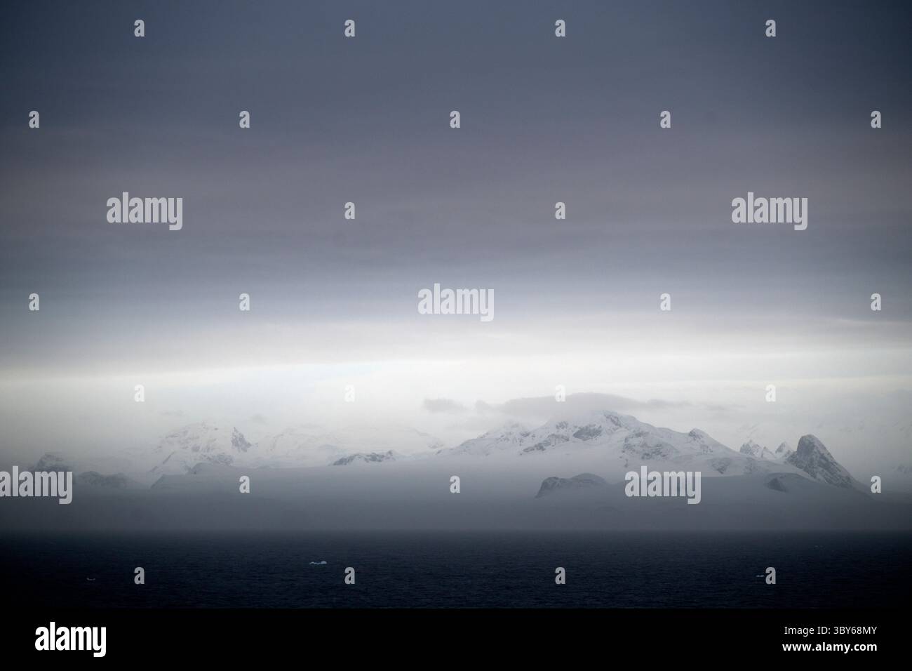 Le soleil levant peint un paysage pastel de nuages et de montagnes quelque part dans le détroit de l'Antarctique, à la pointe nord de la péninsule Antarctique, Ant Banque D'Images