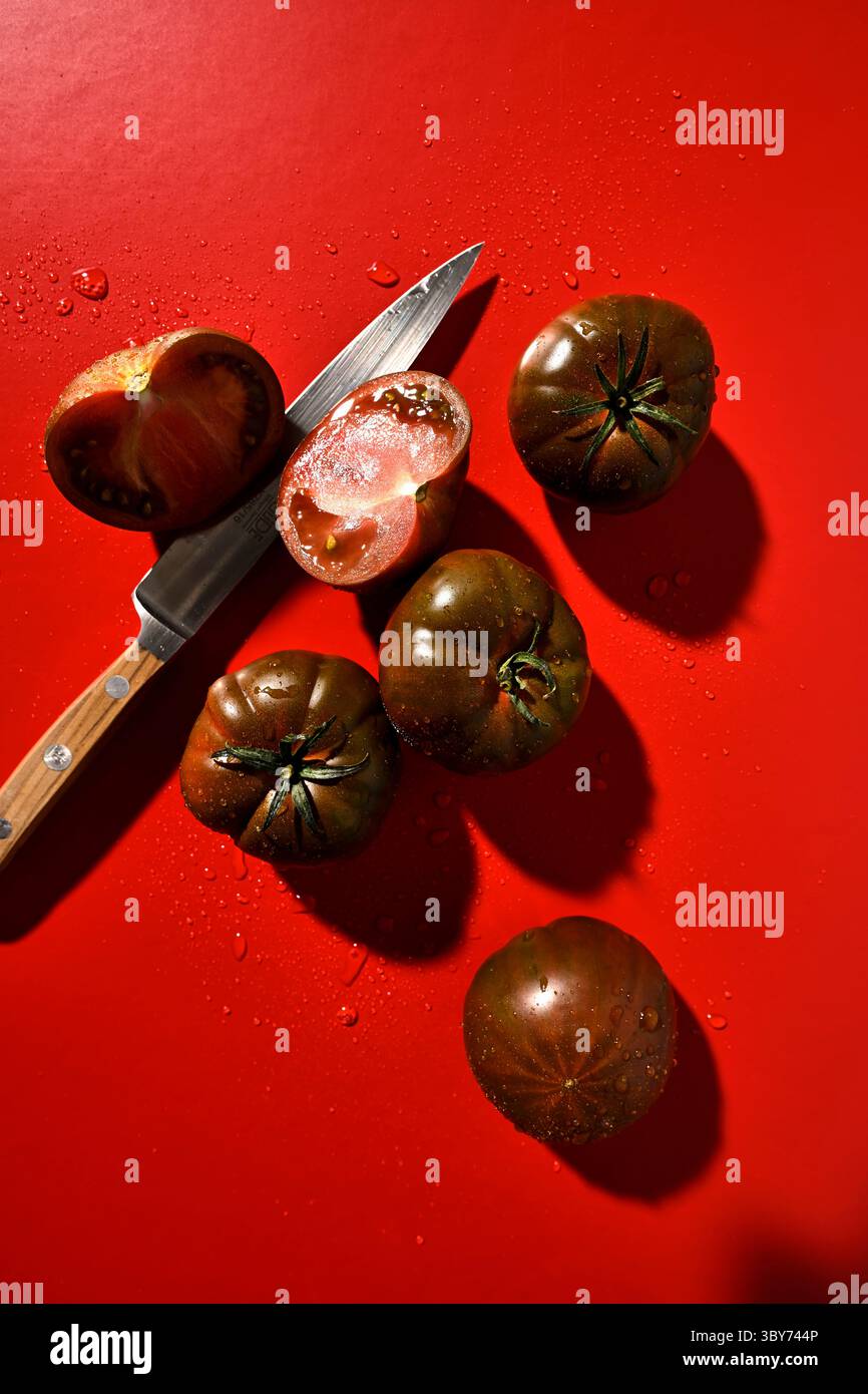 Tomates Marmande avec couteau sur fond rouge Banque D'Images