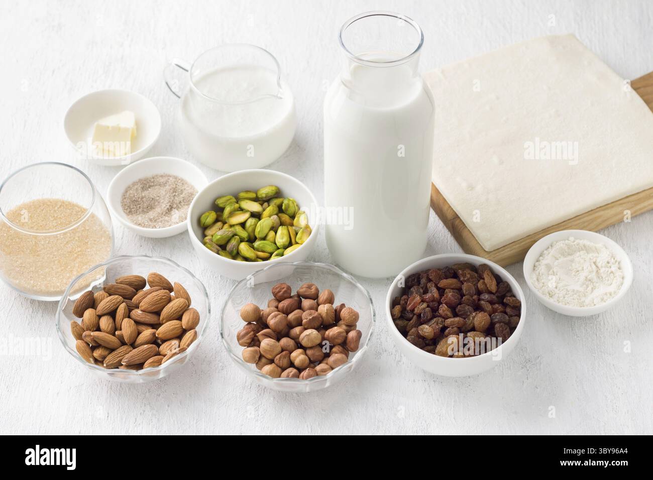 Nourriture, ingrédients pour le dessert arabe traditionnel Umm Ali : noix, raisins secs, lait, crème, cassonade, sucre vanillé, farine, beurre et puf prêt à l'emploi Banque D'Images