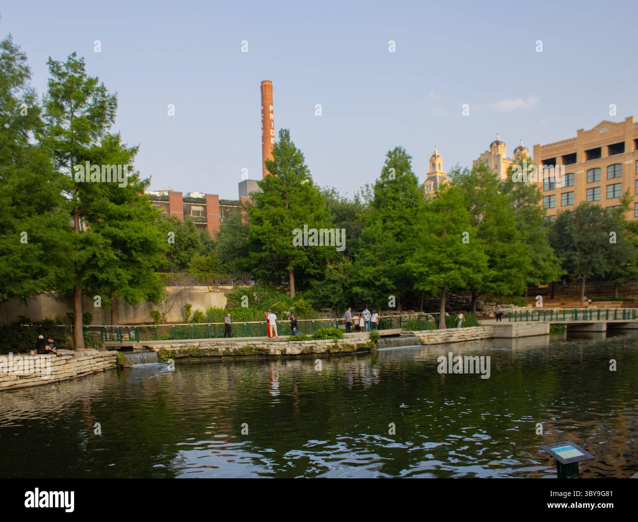 Vue panoramique sur le Pearl District le long de la promenade fluviale de San Antonio, présentant l'architecture historique et les eaux tranquilles au cœur du Texas. Banque D'Images