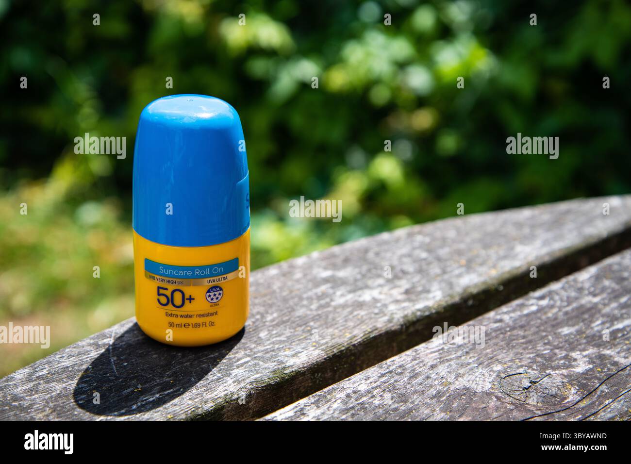 Yellow Factor 50+ écran solaire roll-on avec couvercle bleu, placé sur une table de jardin en bois en plein soleil, évoquant l'été, la sécurité solaire et les loisirs en plein air Banque D'Images Yellow Factor 50+ écran solaire roll-on avec couvercle bleu, placé sur une table de jardin en bois en plein soleil, évoquant l'été, la sécurité solaire et les loisirs en plein air Banque D'Images
