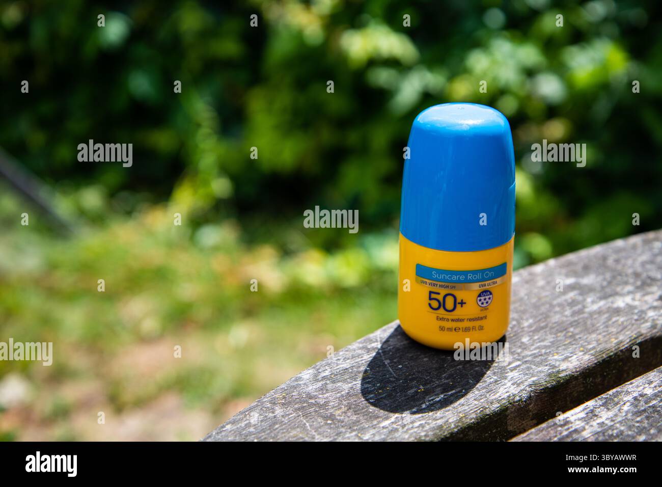 Yellow Factor 50+ écran solaire roll-on avec couvercle bleu, placé sur une table de jardin en bois en plein soleil, évoquant l'été, la sécurité solaire et les loisirs en plein air Banque D'Images Yellow Factor 50+ écran solaire roll-on avec couvercle bleu, placé sur une table de jardin en bois en plein soleil, évoquant l'été, la sécurité solaire et les loisirs en plein air Banque D'Images