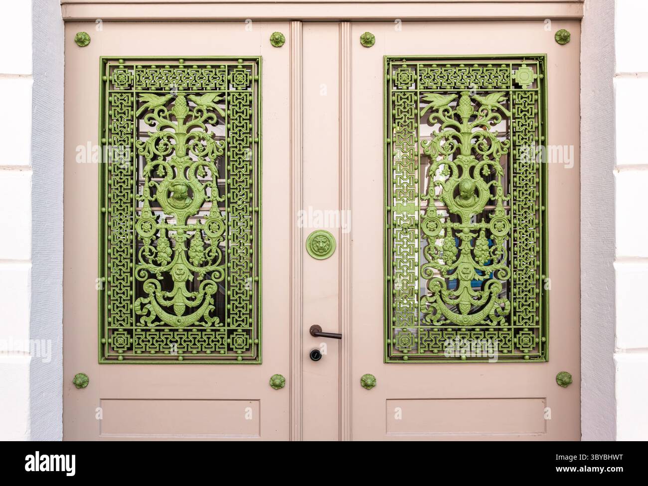 Porte historique à Lubeck avec un design complexe en métal vert. La porte est peinte dans une couleur beige douce, contrastant avec les détails verts vibrants. Banque D'Images