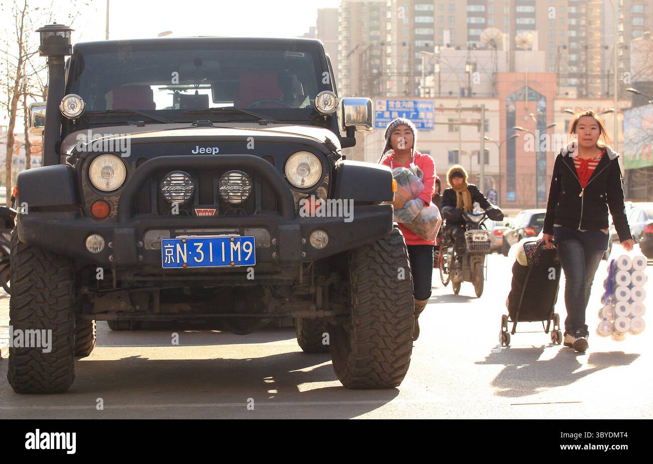 16 décembre 2011, PÉKIN, CHINE : des piétons chinois passent devant une jeep américaine garée sur le trottoir à Pékin le 16 décembre 2011. La Chine imposera des droits punitifs allant jusqu'à 22 pour cent sur les grandes voitures et les VUS exportés des États-Unis, a déclaré le ministère chinois du commerce plus tôt cette semaine, le dernier d'une série de différends commerciaux entre les deux plus grandes économies du monde. (Crédit image : © Stephen Shaver/ZUMA Press Wire) Banque D'Images