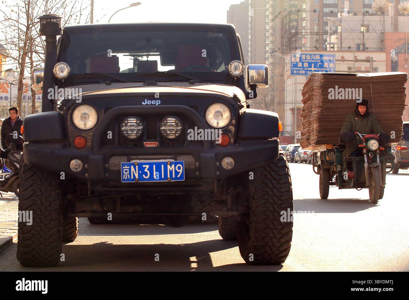 16 décembre 2011, PÉKIN, CHINE : un ouvrier chinois transporte du carton devant une jeep américaine garée sur le trottoir à Pékin le 16 décembre 2011. La Chine imposera des droits punitifs allant jusqu'à 22 pour cent sur les grandes voitures et les VUS exportés des États-Unis, a déclaré le ministère chinois du commerce plus tôt cette semaine, le dernier d'une série de différends commerciaux entre les deux plus grandes économies du monde. (Crédit image : © Stephen Shaver/ZUMA Press Wire) Banque D'Images