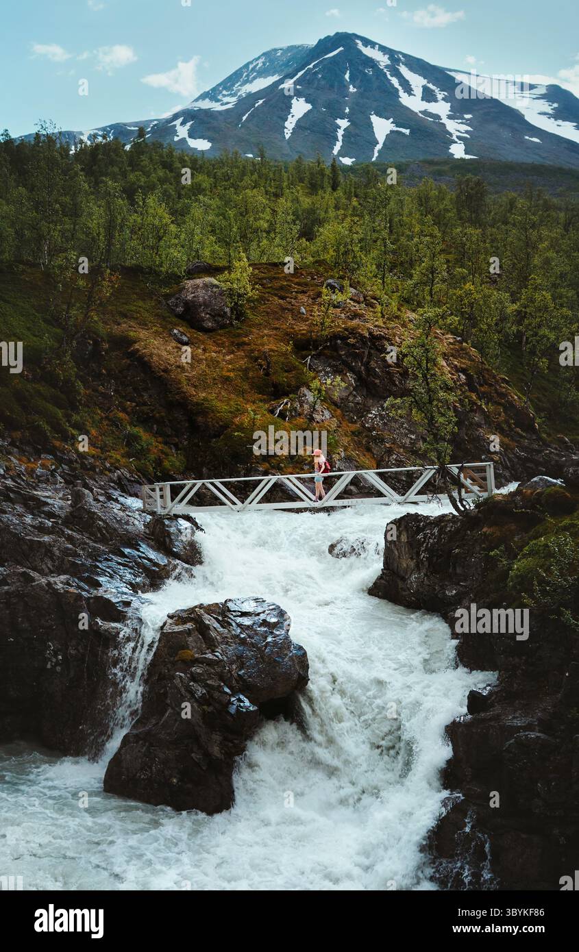 Voyageur randonnée seul dans les montagnes traversant un pont sur la rivière qui coule en Norvège vacances d'été actif aventure tour, fille touriste explorant Lyngen Banque D'Images
