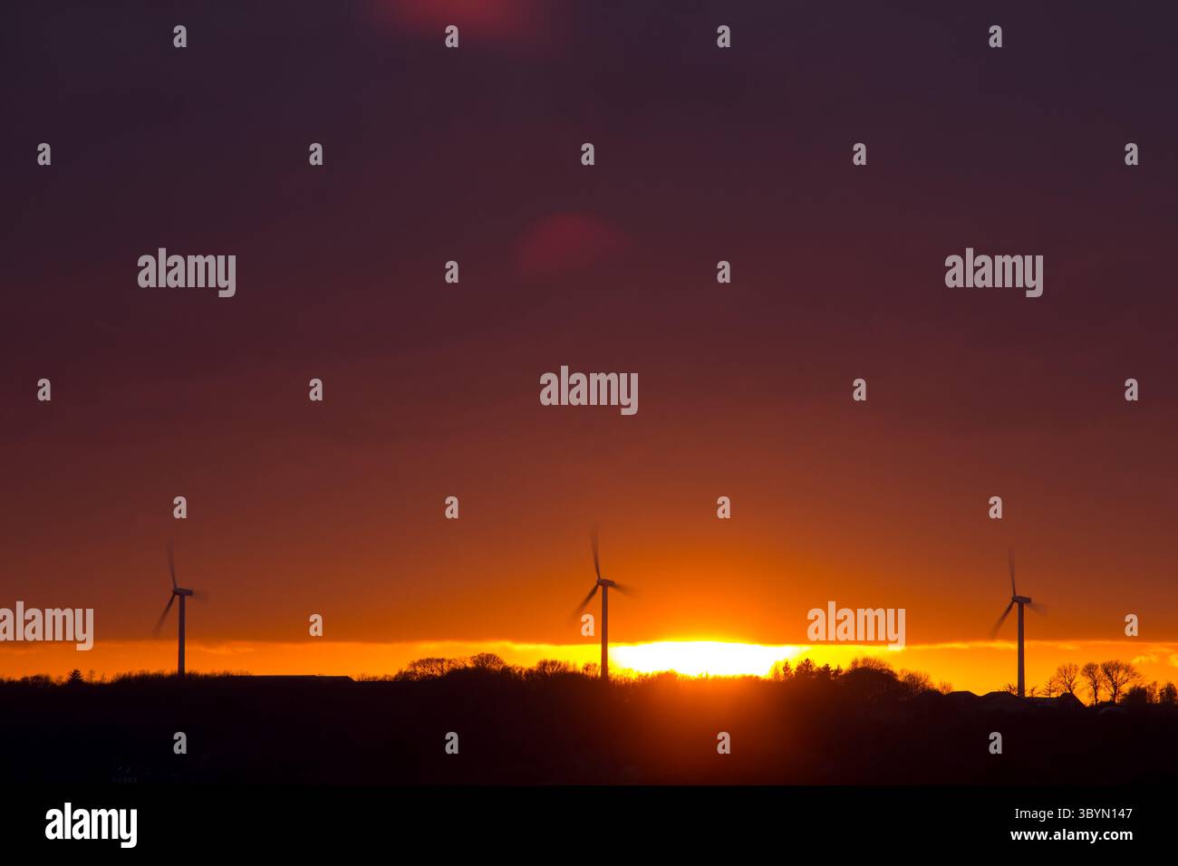Moulin à vent dans le champ au coucher du soleil avec ciel orange, éoliennes sur le champ en Europe créant de l'énergie propre Banque D'Images