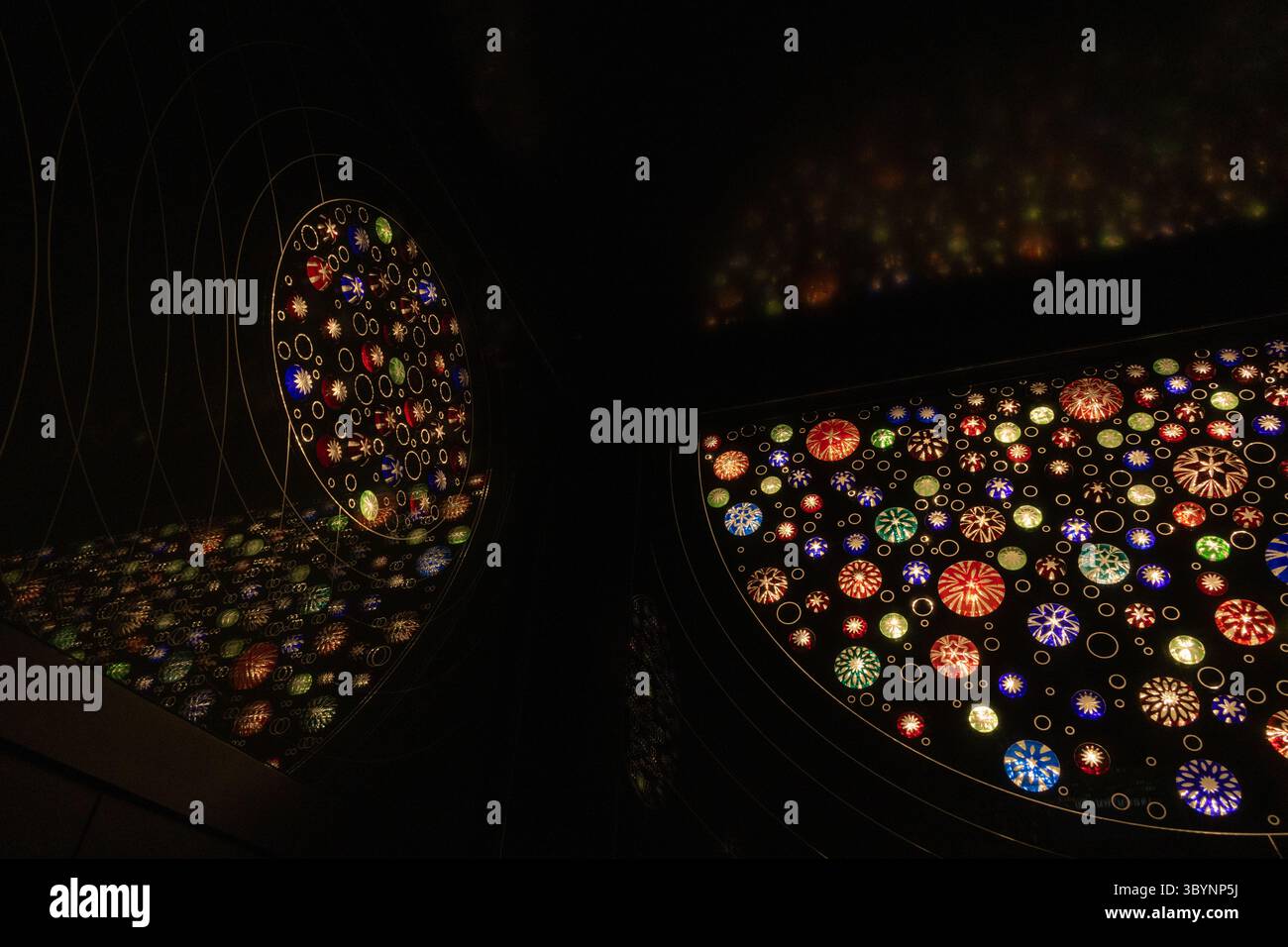 Une pièce avec un design grand, coloré et complexe sur le mur avec réflexion. Le design est composé de nombreuses petites lumières colorées et étincelantes t Banque D'Images