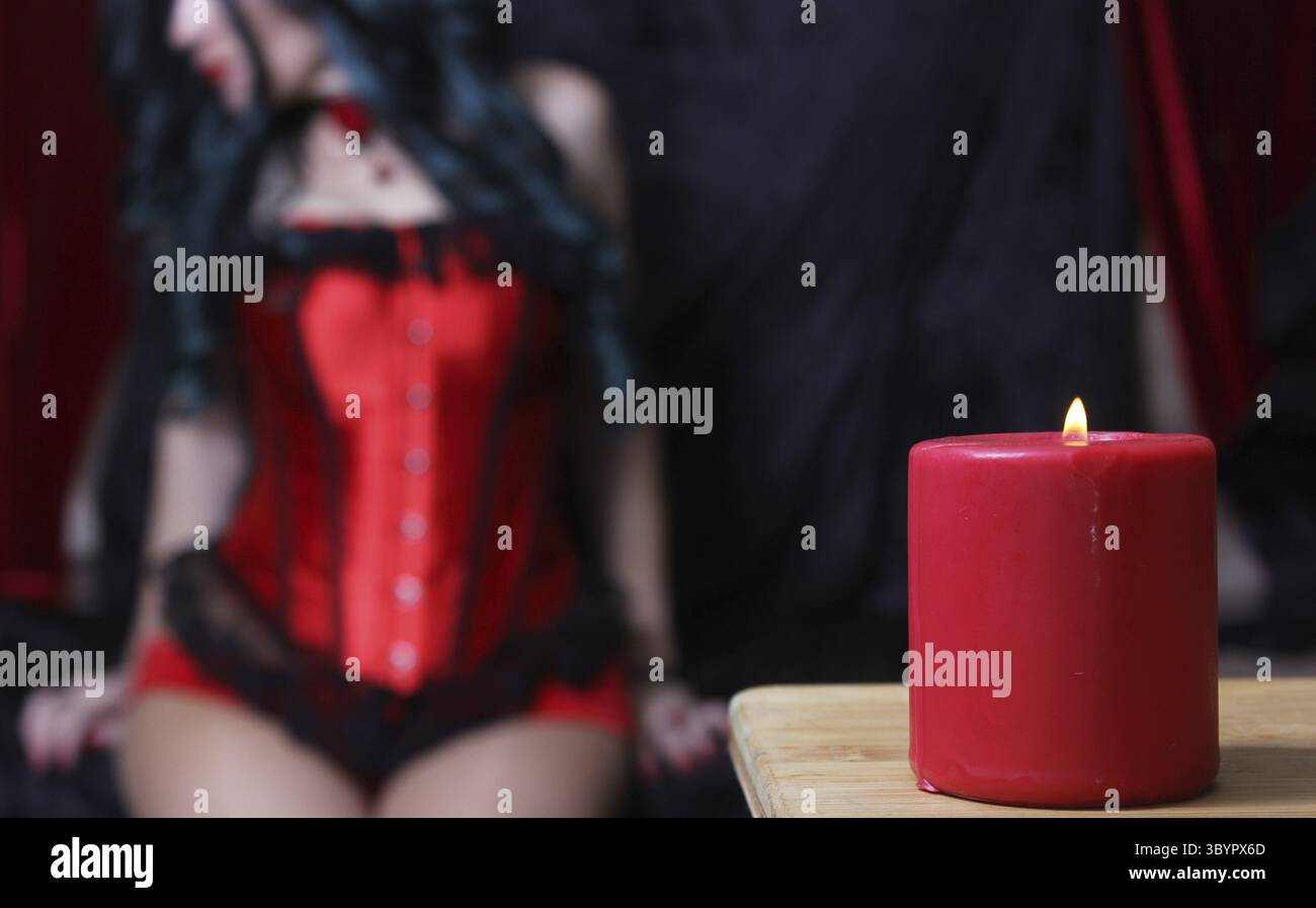 Bougie rouge avec femme en corset rouge en arrière-plan DOF peu profond Banque D'Images