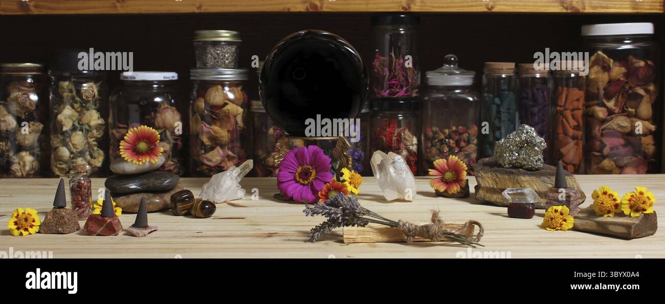 Autel de méditation avec cristaux de roche et fleurs. Grande boule de cristal obsidienne dans les jarres centrales d'herbes en arrière-plan Banque D'Images