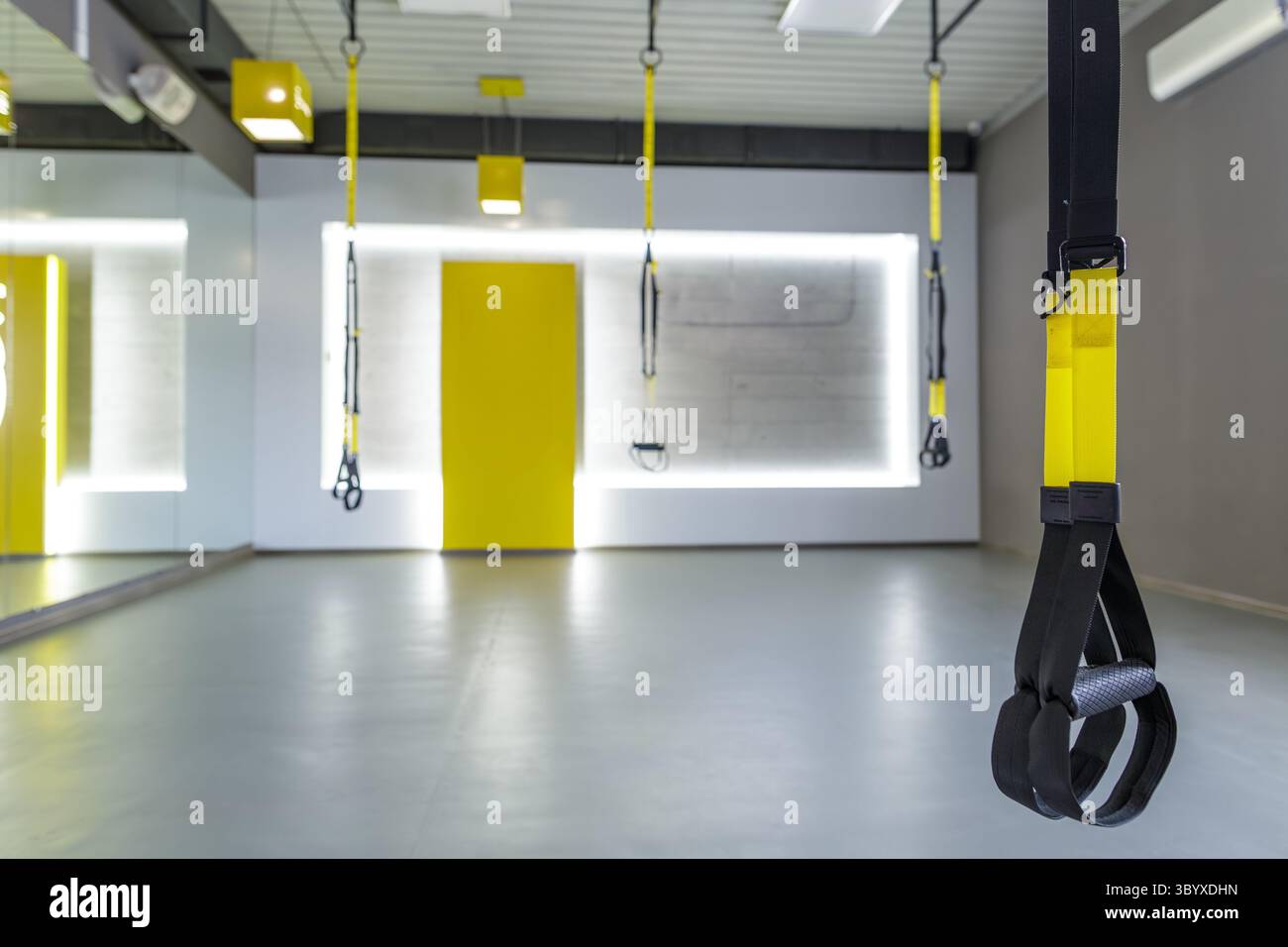 Intérieur de salle de sport contemporain avec sangles d'entraînement suspendues prêtes pour les séances de fitness en groupe et de résistance Banque D'Images