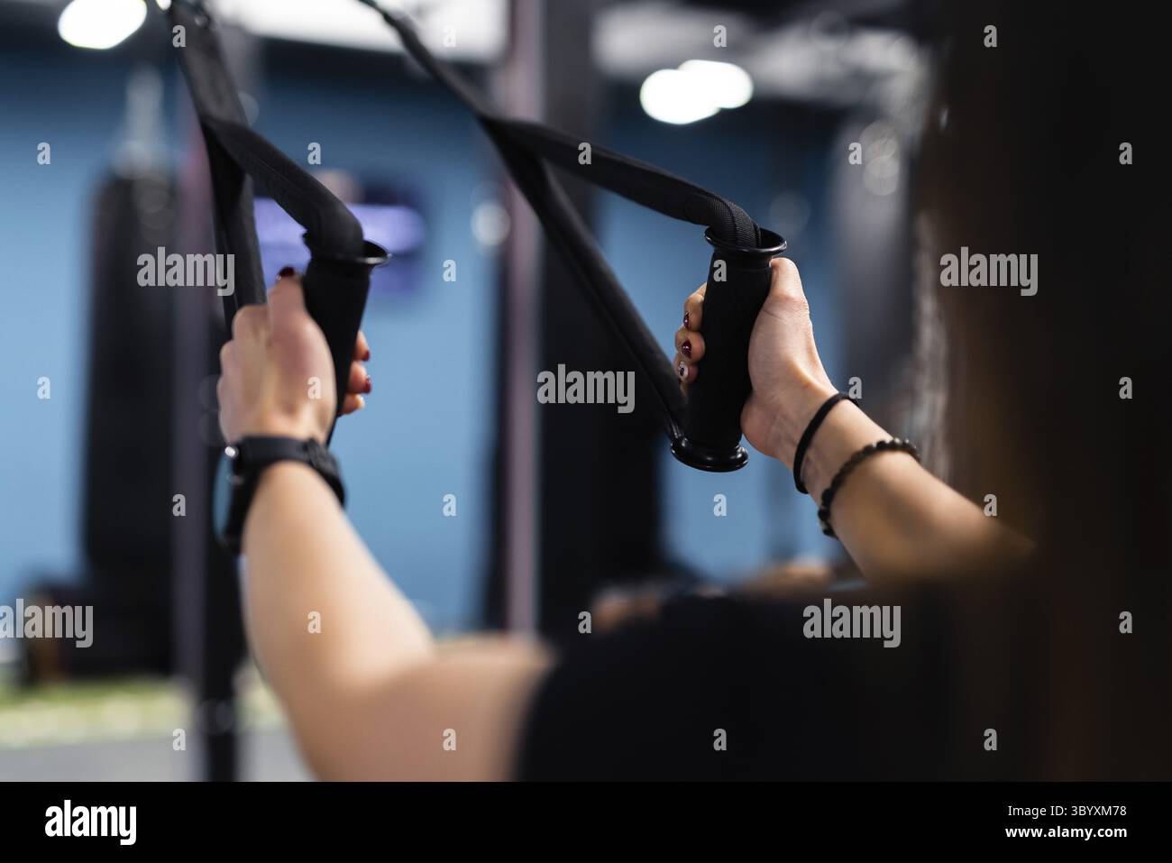 Concept intérieur de gymnastique avec un entraîneur personnel utilisant des équipements d'entraînement. pas de visage portrait d'une jeune fille d'entrainement aux cheveux longs Banque D'Images