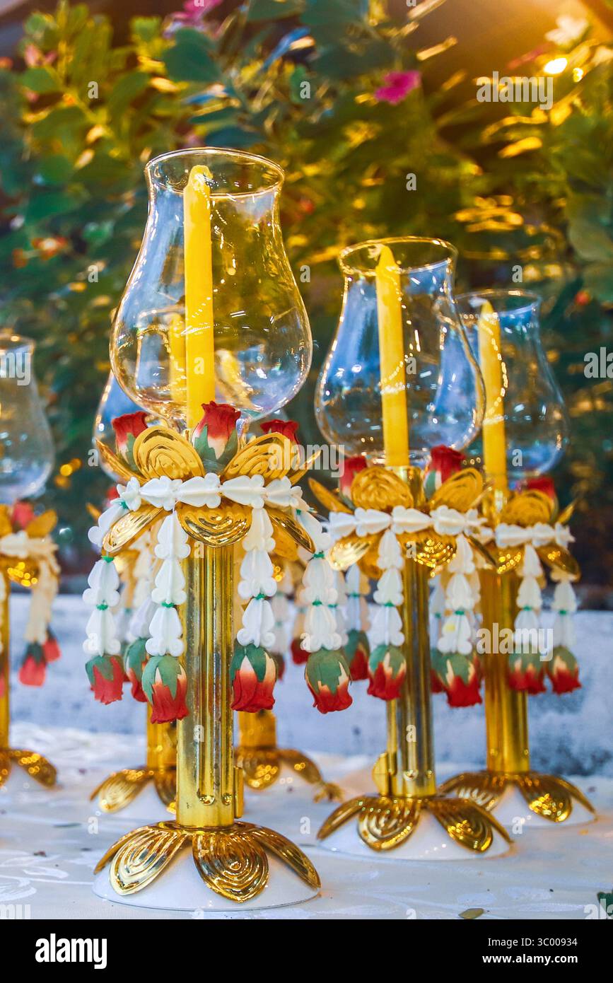 Bougeoir en verre de style thaïlandais avec base dorée et guirlande, utilisé dans les festivals bouddhistes et les cérémonies culturelles, brillant avec une lumière ambiante dorée chaude Banque D'Images