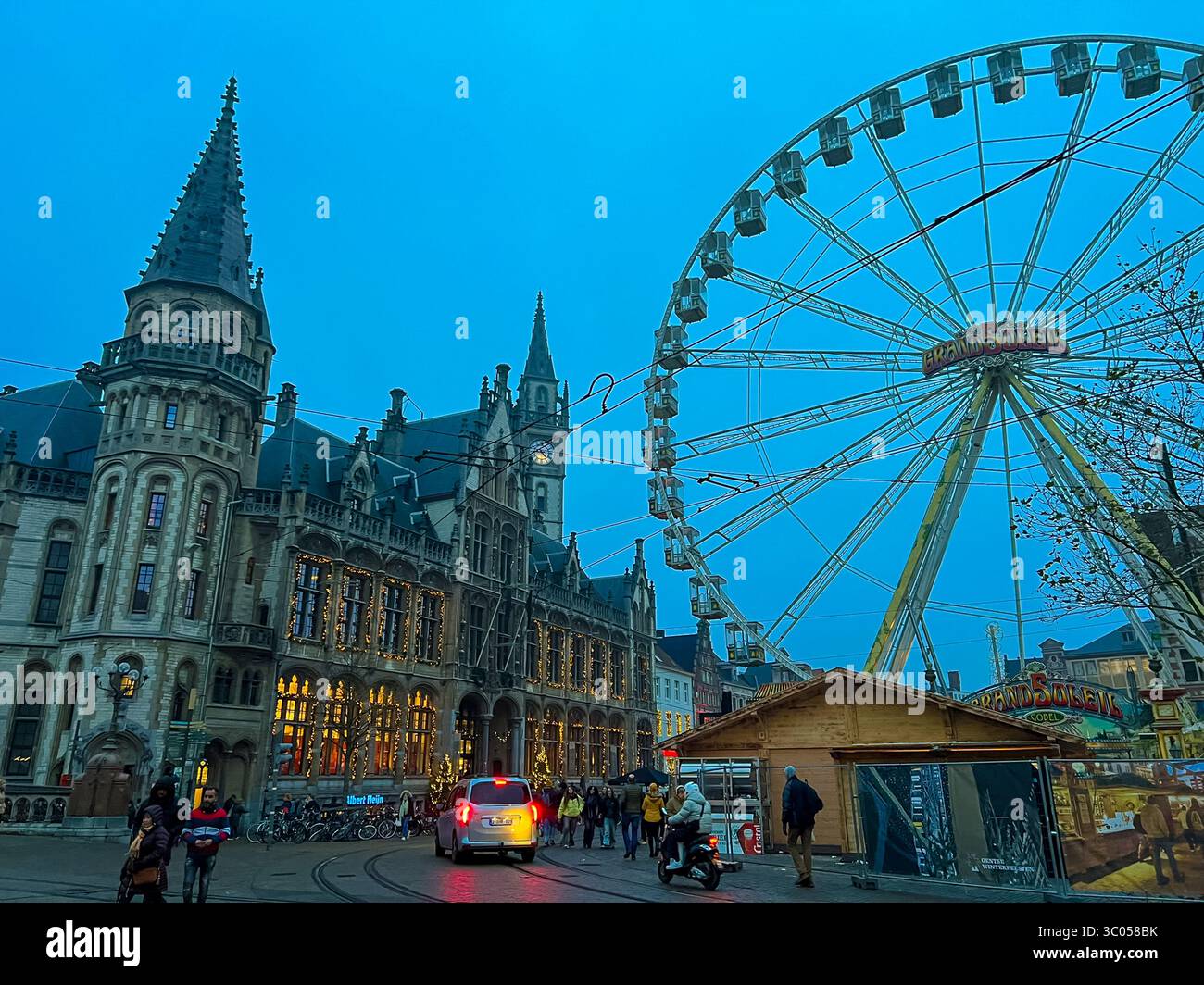 Grande roue festive derrière la cathédrale de Gand avec la lueur du marché de noël Banque D'Images