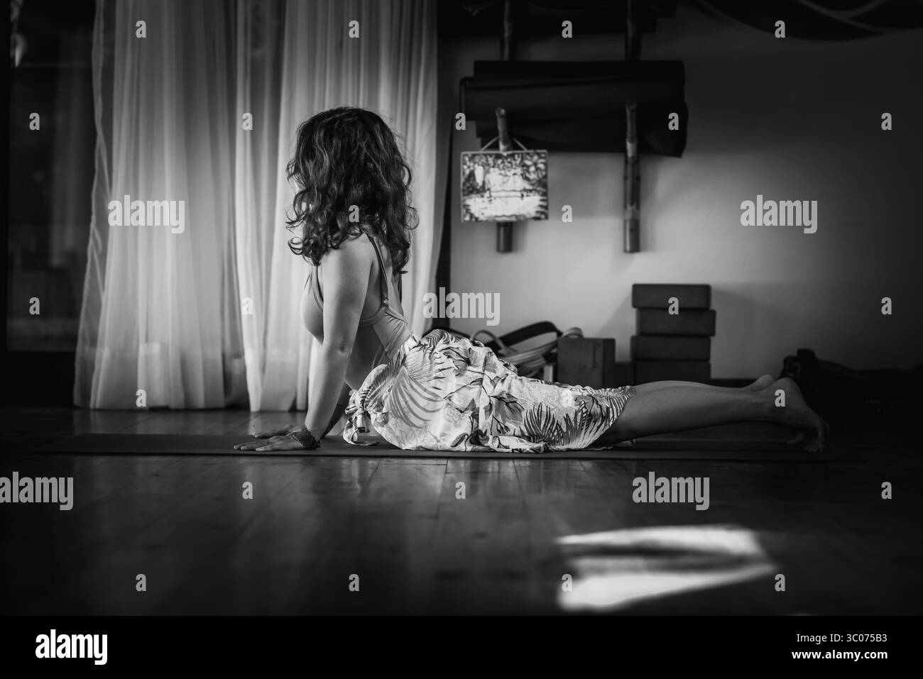 Femme en chien orienté vers le haut pose sur tapis de yoga en monochrome Banque D'Images