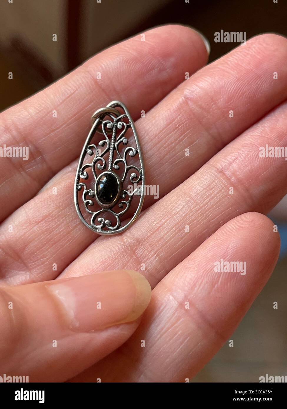 Pendentif jet et argent sur la main. Fermer la vue. Banque D'Images