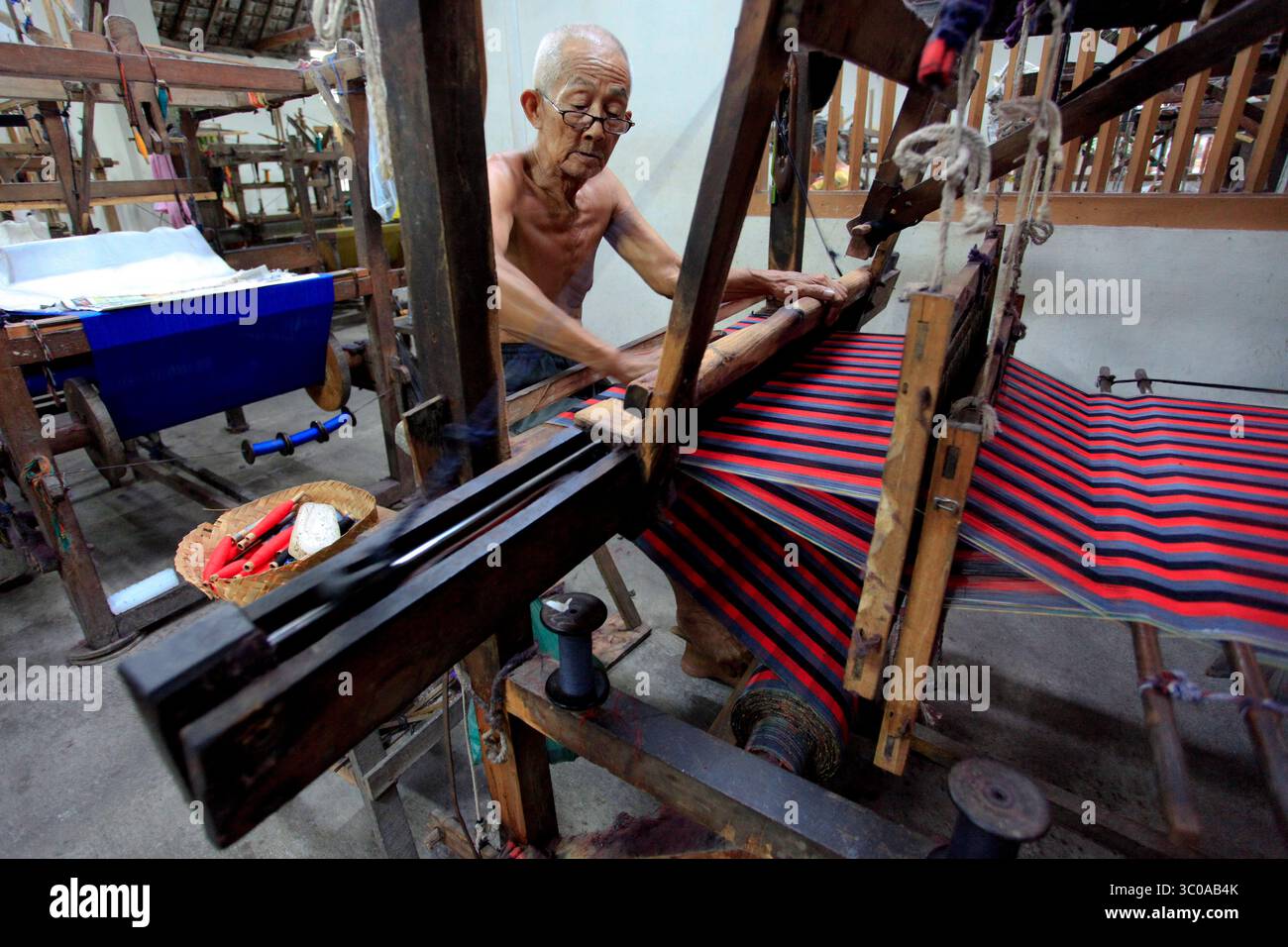 De vieux artisans de tissage travaillent avec un métier non machine (ATBM) à l’usine de tissage traditionnel de Lurik Kurnia. Banque D'Images