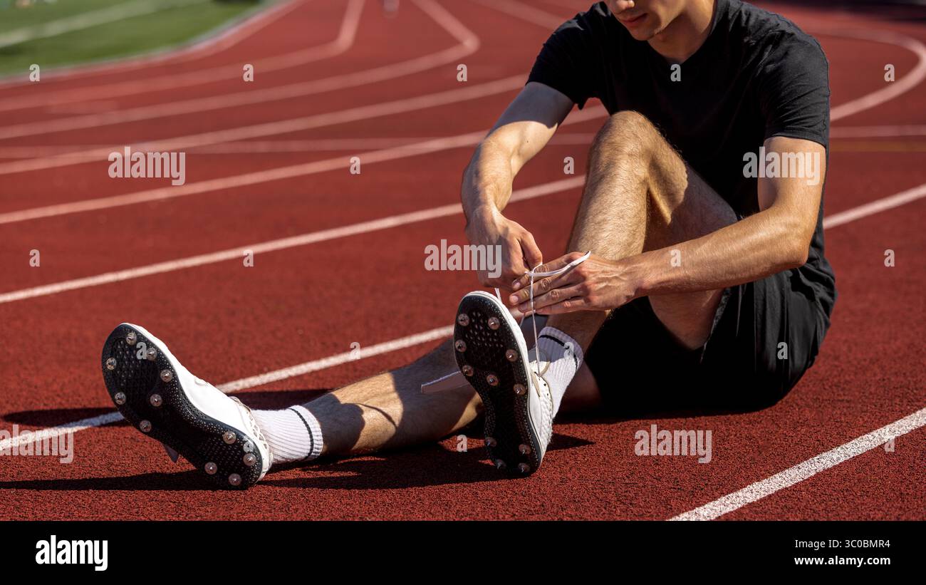 Athlète lacant ses chaussures sur piste avant l'entraînement de sprint Banque D'Images
