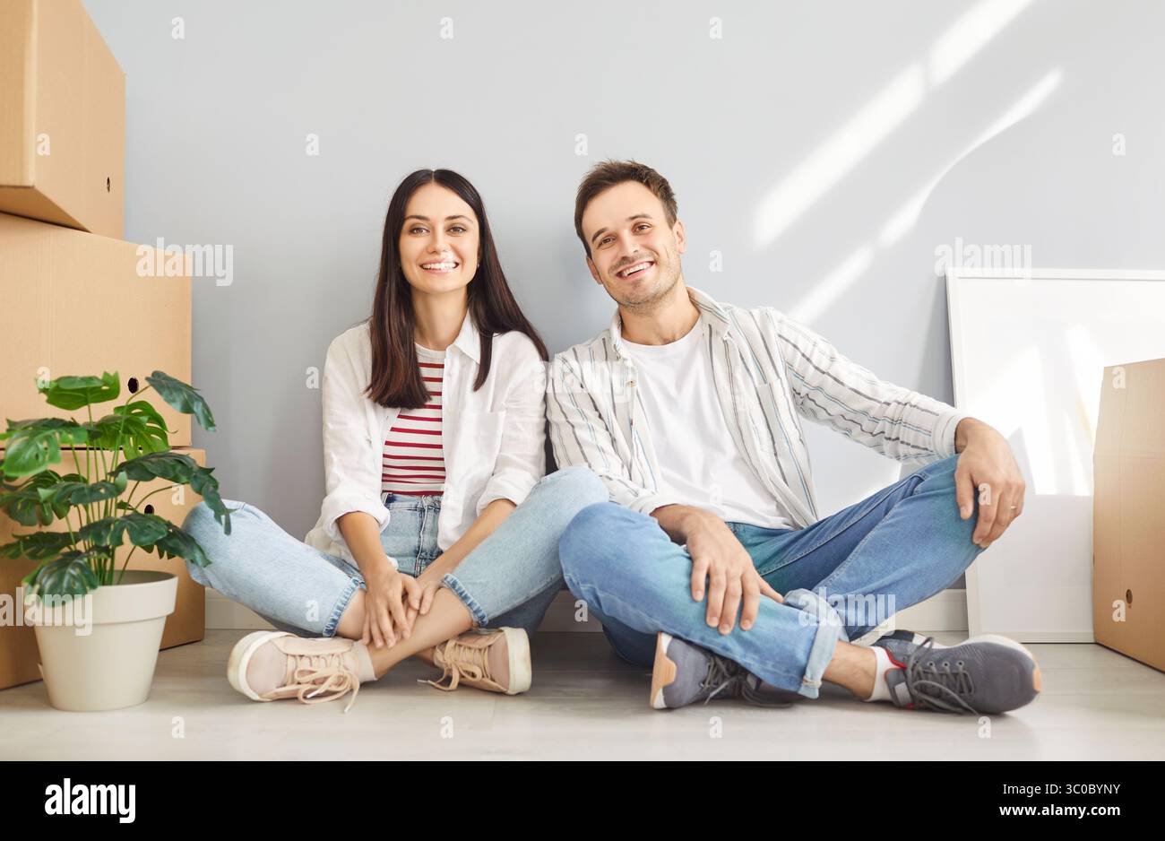 Jeune famille heureuse, propriétaires joyeux déménageant un nouvel appartement, entrer à la maison, des locataires de couple excités assis Banque D'Images