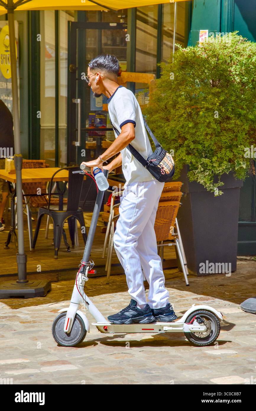 Jeune homme oriental sur scooter électrique dans le centre-ville - Loches, Indre-et-Loire (37), France. Banque D'Images
